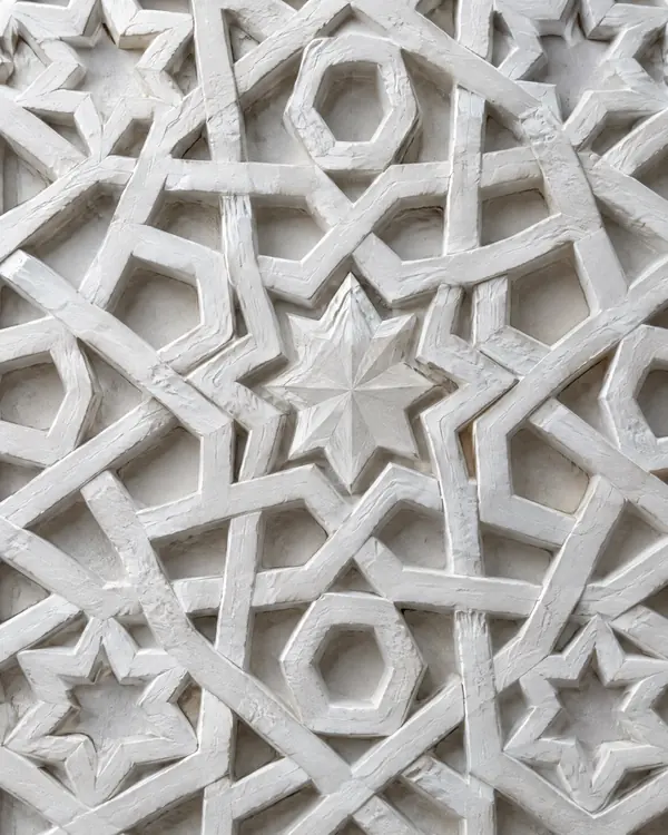 A carved ganch lattice with eight-pointed stars, lit from the side